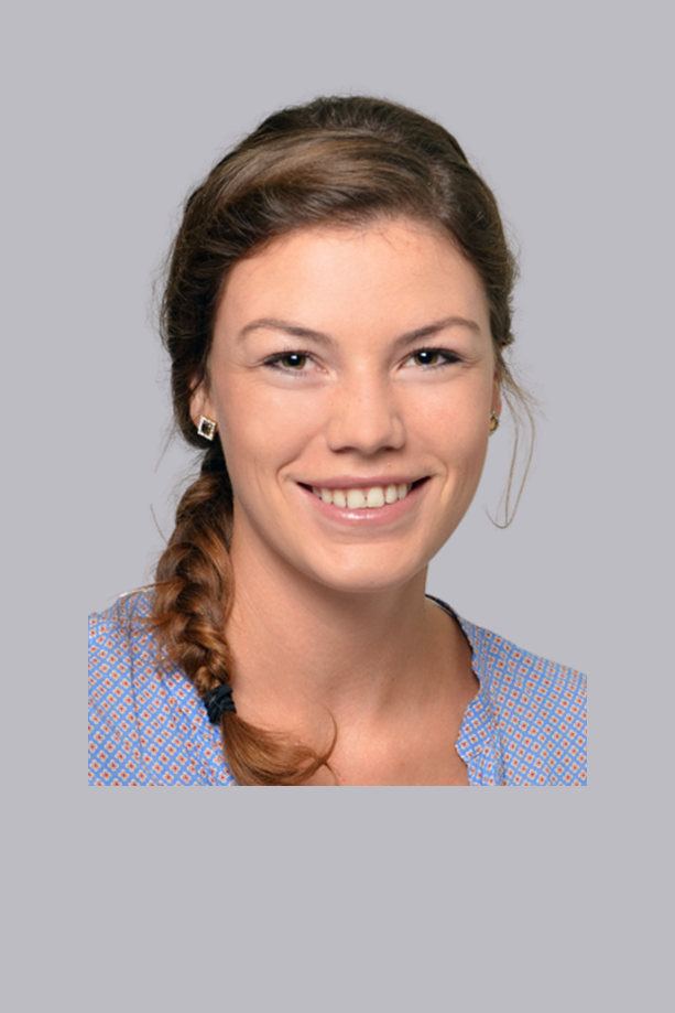 Gros plan sur une jeune femme souriante aux cheveux bruns attachés en queue de cheval, aux dents blanches et portant un chemisier bleu, sur un fond gris clair.