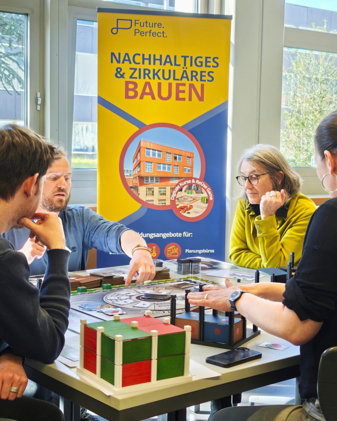 Spielrunde mit dem Re-Use Game an der Constructa-Jahresversammlung, im Hintergrund ein Roll-up von Future Perfect